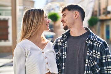 Young man and woman couple hugging each other standing at street