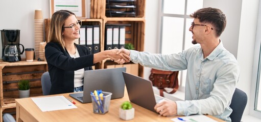 Young man and woman business workers shake hands working at office