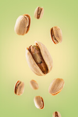 Wallpaper of roasted pistachios floating on light green and yellow background. Clean image for branding.