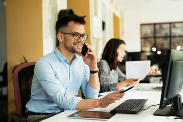 Fototapeta premium Businessman in office. Handsome man talking on phone at work..