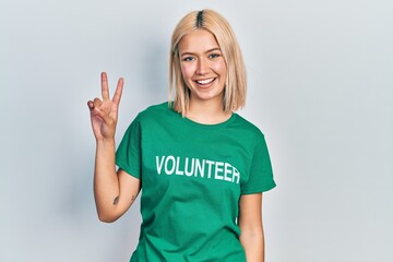 Beautiful blonde woman wearing volunteer t shirt smiling with happy face winking at the camera...