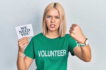 Beautiful blonde woman wearing volunteer t shirt showing we need you banner annoyed and frustrated...