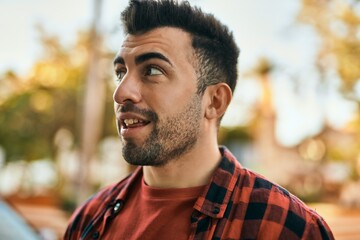 Young hispanic man smiling happy standing at the city.