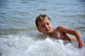 A white teenage boy swims in the sea. Photographed close up