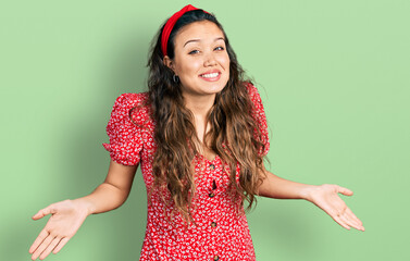 Young hispanic girl wearing casual clothes clueless and confused expression with arms and hands...