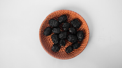 ajwa dates in a rattan plate with white background