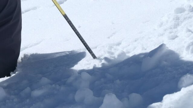 Person testing the snow level, avalanche risk high in the mountains - handheld view