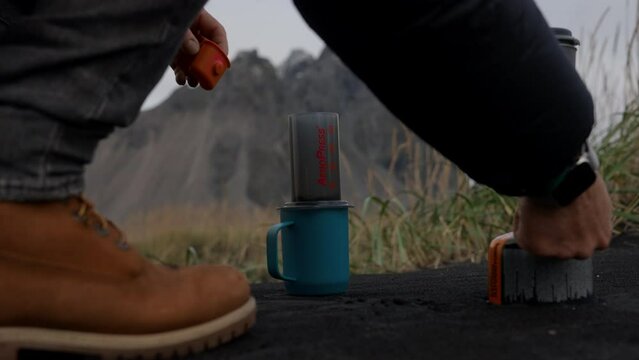 Man Pouring Water Into Cafetiere On Black Sand Beach