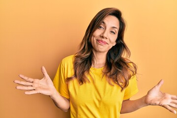 Young latin woman wearing casual clothes clueless and confused expression with arms and hands raised. doubt concept. - obrazy, fototapety, plakaty