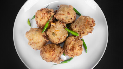 full shot a plate of vegetable fritters in a black background
