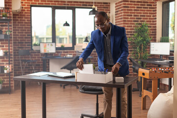 Person getting fired and gathering belongings in box to leave business job. Disappointed man being discharged from work and packing up office things. Frustrated adult being dismissed