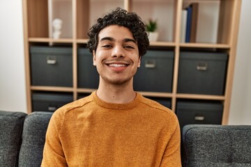 Fototapeta premium Young hispanic man smiling happy sitting on the sofa at home.