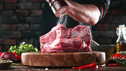 Chef pouring salt from grinder on raw meat steak
