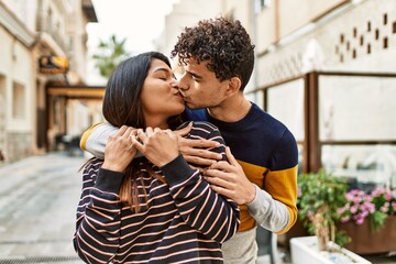 Fototapeta premium Young latin couple smiling happy and hugging at the city.