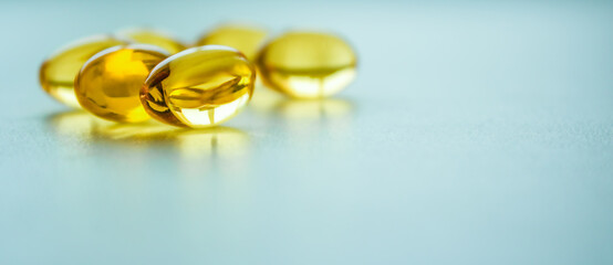 Fish oil capsules on a blue background with copy space.