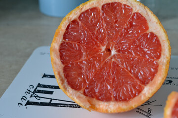 slice of ripe juicy red grapefruit half on light background. vitamins and organic food concept.