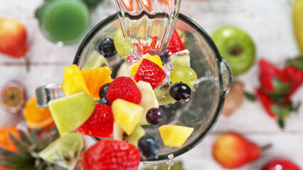 Falling pieces of fruits and vegetables into blender.