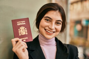 Young beautiful businesswoman smiling happy holding spainish passport at the city.