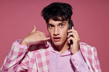 A young man fashionable talking on the phone pink blazer posing studio pink background unaltered