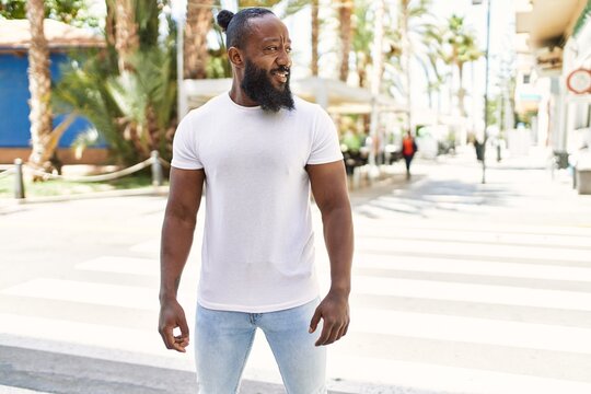 Handsome african american man with beard wearing casual white t shirt outdoors on a sunny day