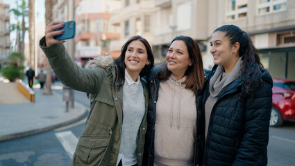 Mother and daugthers making selfie by the smartphone standing together at street