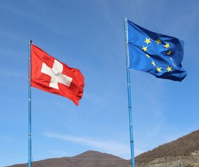 Flags of Switzerland and European Union fly together at the state border
