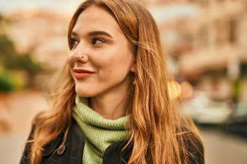 Young blonde girl smiling happy standing at the city.