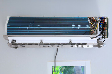 front view bare indoor unit of air conditioner reveals blue aluminum fins, copper pipes and wires...
