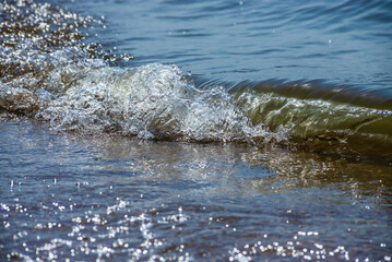 Sea wave with spray and foam near the shore