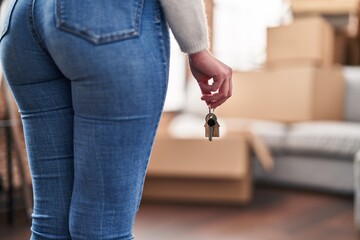 Obraz premium Young blonde woman holding key standing at new home