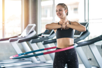 Young woman doing hula hoop during an exercise class in fitness gym. Healthy sports lifestyle, Fitness, Healthy concept - obrazy, fototapety, plakaty