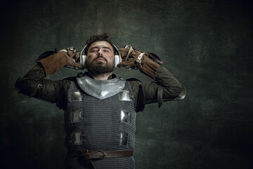Romantic medieval warrior or knight with dirty wounded face in headphones listening to music...