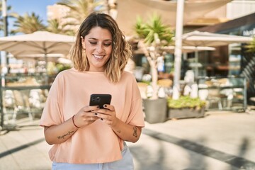 Young hispanic woman smiling confident using smartphone at street