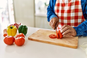 Senior man cutting tomato at kitchen