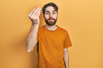 Caucasian man with beard wearing casual yellow t shirt doing italian gesture with hand and fingers confident expression