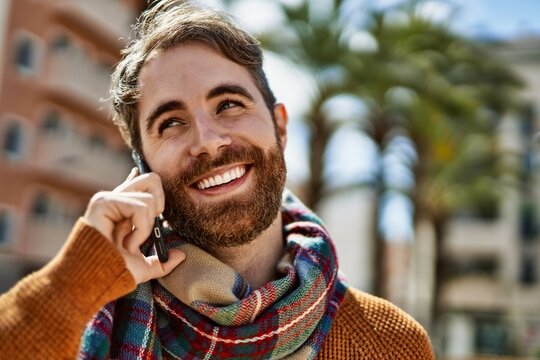 Caucasian man with beard having a conversation speaking on the phone outdoors on a sunny day