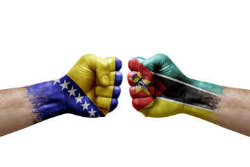 Two hands punch to each others on white background. Country flags painted fists, conflict crisis concept between bosnia and mozambique