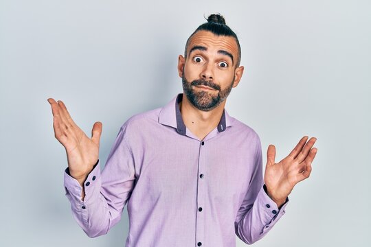 Young hispanic man wearing casual clothes clueless and confused with open arms, no idea and doubtful face.