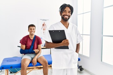 Fototapeta premium Two men physiptherapist and patient having rehab session holding clipboard at clinic