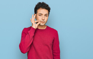 Young handsome man wearing casual clothes mouth and lips shut as zip with fingers. secret and...