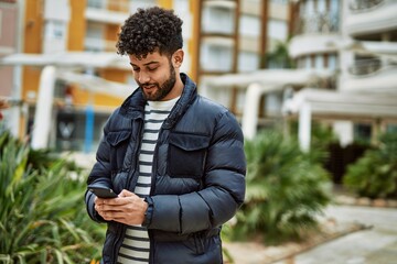 Fototapeta premium Young arab man using smartphone outdoor at the town