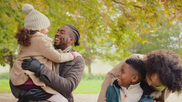 Portrait of smiling family with parents with children on walk through autumn countryside together looking at camera - shot in slow motion