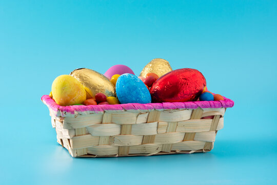 Colorful Chocolate Easter Eggs In A Basket On Blue Background