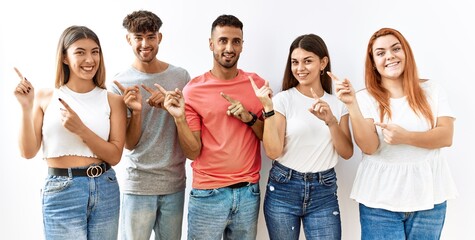 Group of young friends standing together over isolated background smiling and looking at the camera...