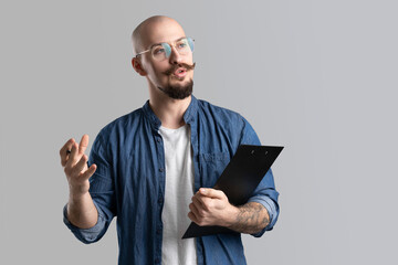 young teacher lectures to students while holding clipboard in hand isolated on gray background 