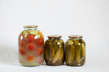canned homemade tomatoes and cucumbers in jars on a white background close up