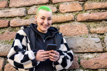 portrait of young authentic androgynous woman with short haircut and colored green, genuine smiling...