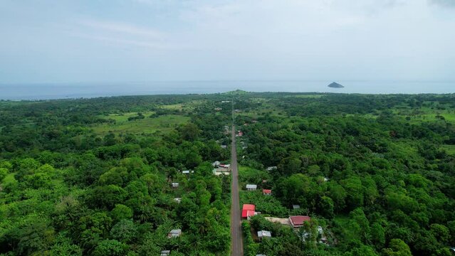 Aerial drone view overlooking a long straight road from the Micolo village, to the coast of Sao Tome, Africa