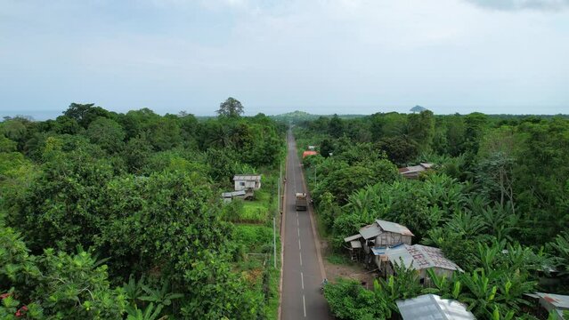 Aerial drone view following a truck driving on a long village road, in west Africa
