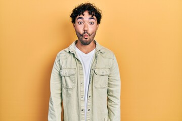 Fototapeta premium Young hispanic man wearing casual clothes making fish face with lips, crazy and comical gesture. funny expression.